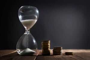 SGP Credit - Personal Loan With Low Interest Rate | Hourglass with coins on wooden table on gray background