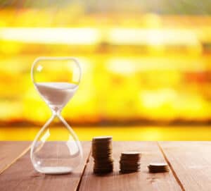 SGP Credit - Personal Loan With Low Interest Rate | Hourglass with coins on wooden table on bright background