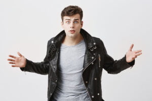 SGP Credit - Personal Loan With Low Interest Rate | Shocked angry caucasian man in black leather jacket, looks with eyes popped, raising his arms, finds out how much debts he has. Stunned male student being alarmed after expelling from college.