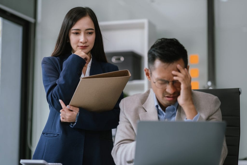 Sad business team is sitting at table covering his face with his hand and talking on cell phone On desk is laptop tablet computer Stress